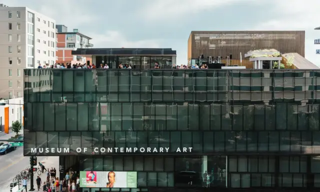 People gather on the rooftop of the Museum of Contemporary Art Denver, enjoying the city views. Photos of the museum showcase its modern architecture.
