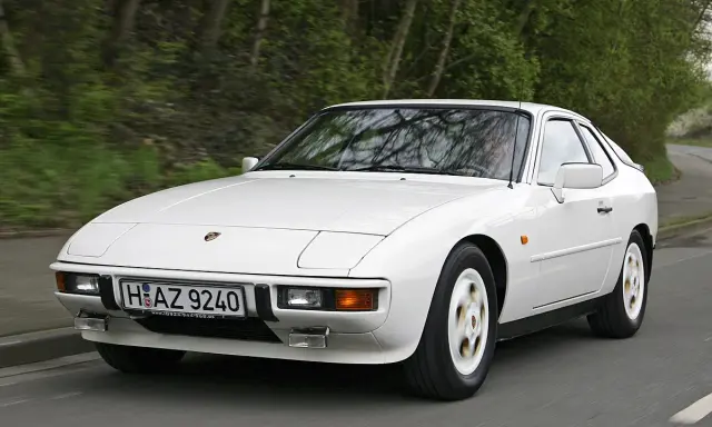Weißer Porsche 924 fährt auf einer Straße. Der geringe porsche 924 verbrauch macht ihn zu einem sparsamen Klassiker.