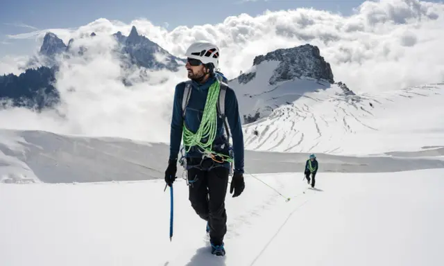 Dwóch alpinistów na ośnieżonym szczycie. Jeden z nich, z czekanem w dłoni, pokazuje, jak dobrać czekan do wspinaczki.
