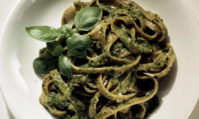 Herzhafte Bandnudeln mit cremiger Pistazien-Pesto-Sauce und frischem Basilikum garniert.