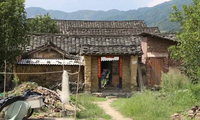 Maison en terre crue, toits de tuiles anciennes, montagnes en arrière-plan. Le prix d'une telle demeure est abordable.