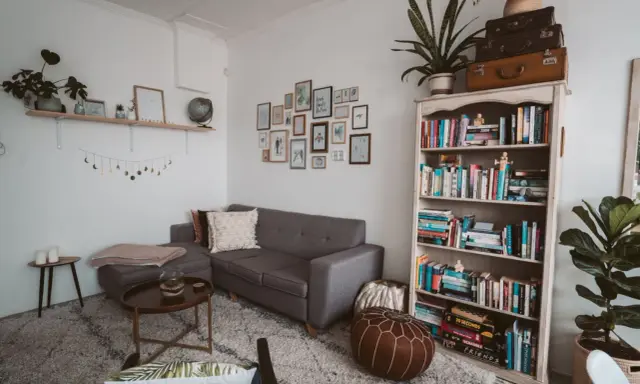 Galeria ścienna z ramkami i girlanda księżycowa nad szarą kanapą. Idealne rozwiązanie, na czym powiesić obraz bez wiercenia.