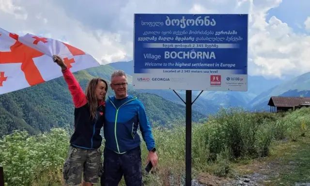 Para podróżników z flagą Gruzji w Bochorna, najwyżej położonej osadzie w Europie. Odpowiedź na pytanie: czy w Gruzji jest bezpiecznie? Tak!
