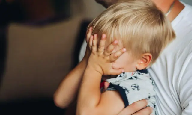 2,5-letnie dziecko budzi się w nocy z płaczem, ukrywając twarz w dłoniach. Tata tuli go, próbując uspokoić.