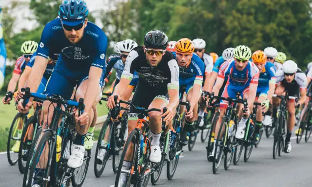 Ciclisti in gara, concentrati e determinati, seguono le loro tabelle allenamento ciclismo per raggiungere la vittoria.