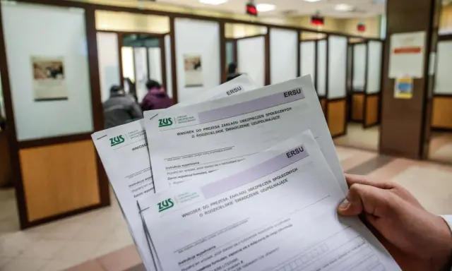 Dłoń trzyma formularze ZUS dotyczące wniosku o rodzicielskie świadczenie uzupełniające. To krok do ponownego przeliczenia emerytury ze względu na długość życia.