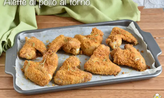 Alette di pollo al forno dorate e croccanti, guarnite con rosmarino fresco, pronte per essere gustate.