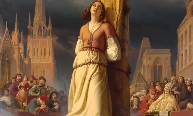 Święta Joanna d'Arc przywiązana do słupa, otoczona tłumem i budynkami sakralnymi.