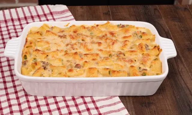 Un invitante pasta al forno bianca, con maccheroni dorati, piselli e carne macinata, gratinata al punto giusto.