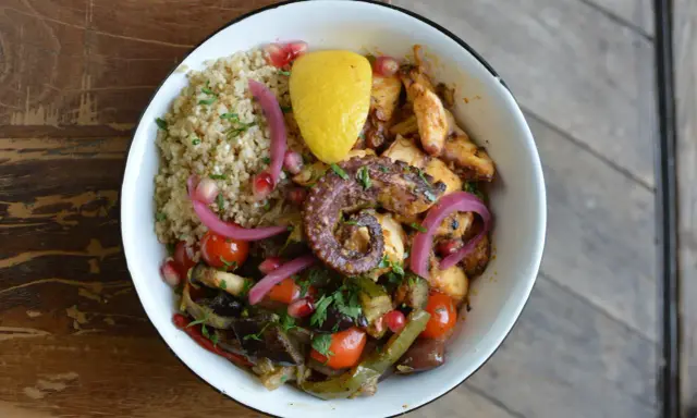 Un plat coloré avec du poulpe grillé, du quinoa, des légumes rôtis et une touche de citron. La marinade pour poulpe grillé a sublimé ce plat.