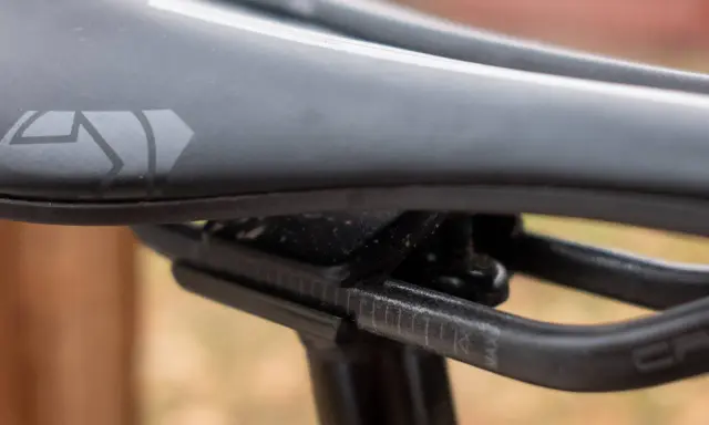 Szukasz idealne siodełko do mtb? Zobacz zbliżenie na czarne siodełko rowerowe z logo i oznaczeniami regulacji.
