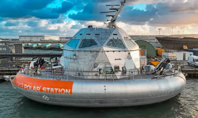 Le bateau Tara Polar Station, une station polaire futuriste, est amarré dans un port sous un ciel dramatique.