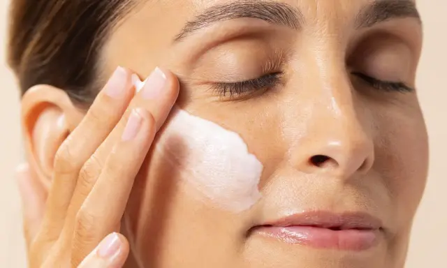 Application d'une crème hydratante contenant de l'acide polyglutamique sur le visage d'une femme.