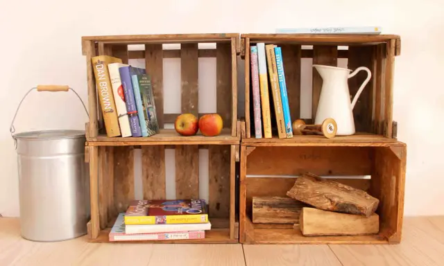 Alte Weinkisten-Ideen: Bücher, Äpfel, eine Kanne und Holzscheite schaffen rustikales Flair.