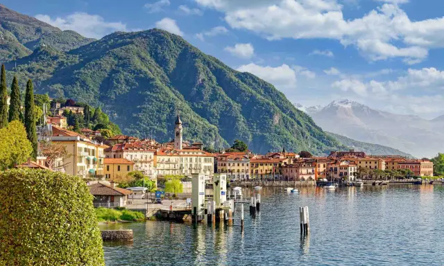 Vista di un paese sul lago d'Iseo, con montagne verdi sullo sfondo. La profondità del lago d'Iseo è suggerita dalla vastità dell'acqua.