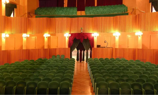 L'arena della regina cattolica, un teatro con poltrone verdi e sipario rosso, attende il pubblico.
