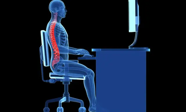 Illustration d'une colonne vertébrale rouge sur un squelette bleu assis à un bureau. L'ergonome définit la posture idéale pour éviter les douleurs.