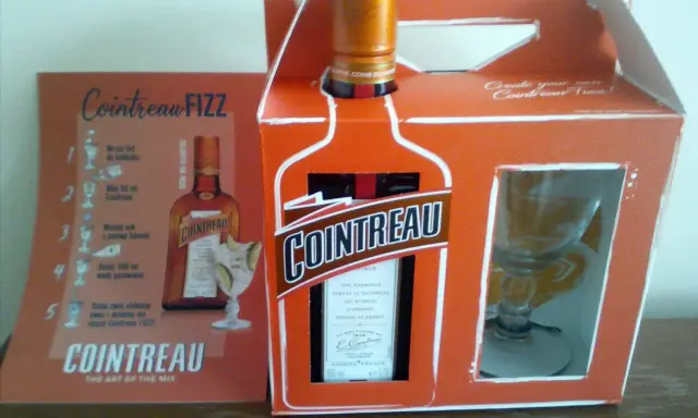 Zestaw Cointreau z kieliszkiem i instrukcją przygotowania drinka Cointreau Fizz. Ten pomarańczowy likier, znany jako Cointreau triple sec, to klucz do orzeźwiających koktajli.