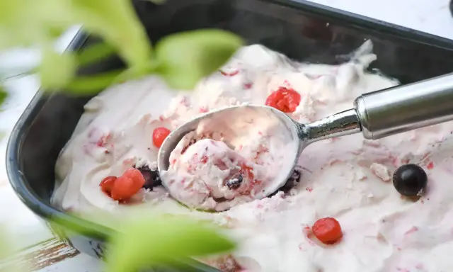 Glace au yaourt italienne aux fruits rouges, servie dans un bac avec une cuillère. Parfait pour une recette facile et rafraîchissante.