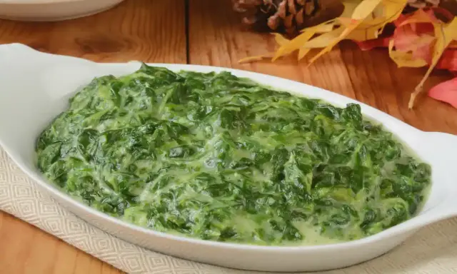 Un plat de épinards à la crème crémeux et appétissant dans un plat blanc, prêt à être dégusté.