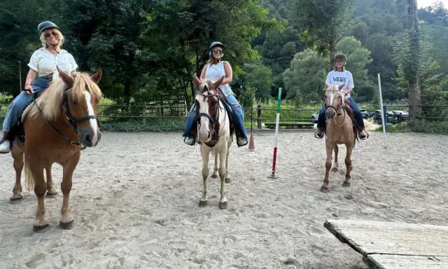 Tre donne si godono una passeggiata a cavallo in Lombardia, con un uomo che le osserva.