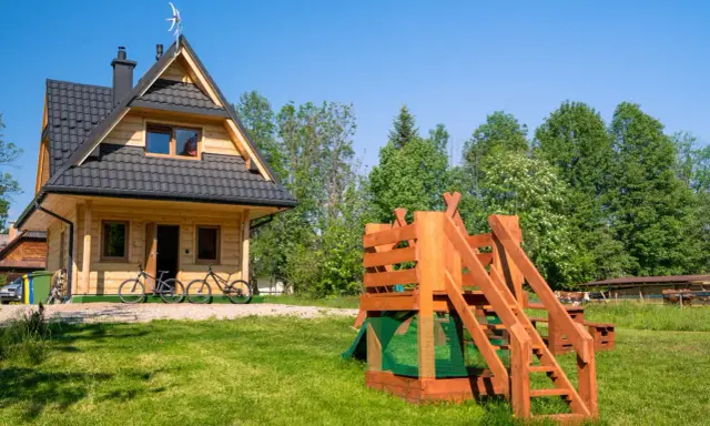 Drewniany domek w Bukowinie Tatrzańskiej z placem zabaw i rowerami przed wejściem. Idealne miejsce na rodzinne wakacje.