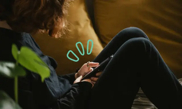 Une personne aux cheveux roux utilise son smartphone, symbolisant quelles peuvent être les principales conséquences de la cyberdépendance : isolement, anxiété, perte de temps.