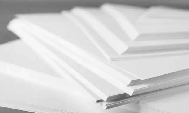 Stosy białego papieru offsetowego ułożone warstwowo, tworząc geometryczne kształty.