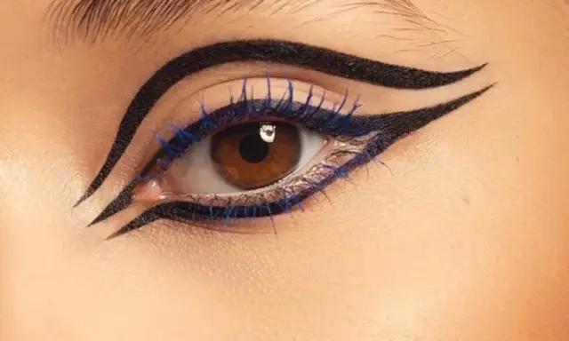 Ojo con delineado dramático y pestañas azules, inspirado en el maquillaje egipcio.