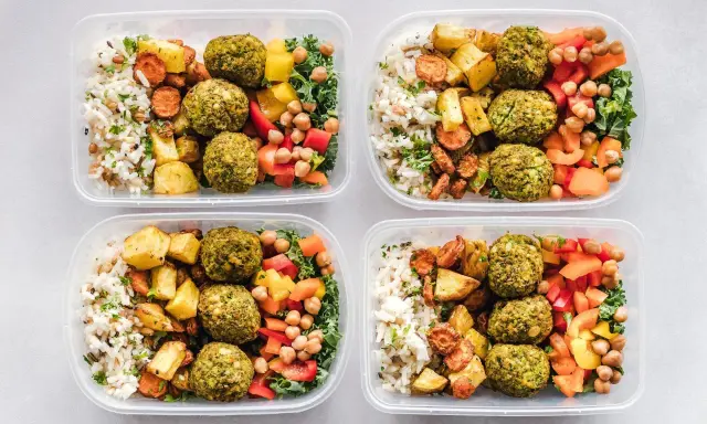 Vier Behälter mit leckeren meal prep Rezepten: Reis, gebratenes Gemüse, Falafel und bunte Paprika.
