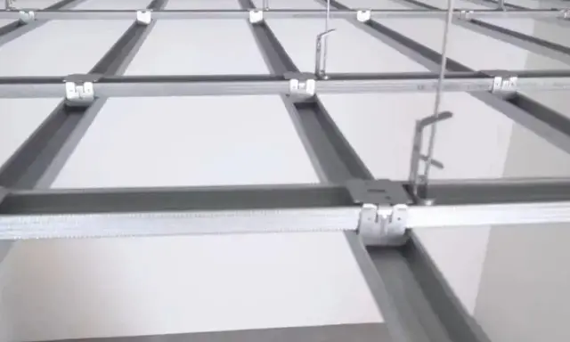 System podwieszanego sufitu w trakcie montażu. Metalowa konstrukcja z profili i wieszaków, gotowa na panele. Jak podwiesić sufit? Zobacz, jak to działa.