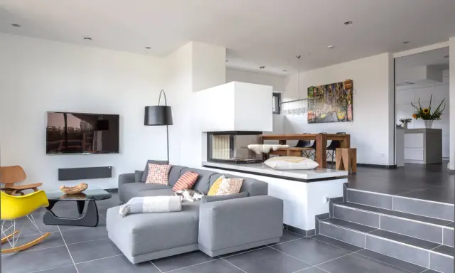 Modernes Split-Level-Haus mit offenem Wohnbereich, Kamin, Essbereich und Küche. Ein Kater döst auf dem Sofa.
