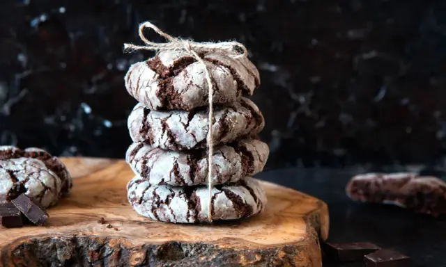 Pile de craquelins au chocolat, parfaits pour une recette facile. Ils sont liés par une ficelle et posés sur une planche en bois.