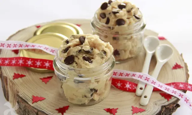 Två glasburkar fyllda med chokladbitsdeg, perfekt för ett enkelt cookie dough recept. Dekorerat med julband och små granar.