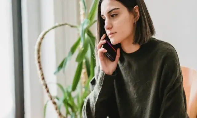Zmartwiona kobieta rozmawia przez telefon, zastanawiając się, czy pracodawca może cofnąć urlop.