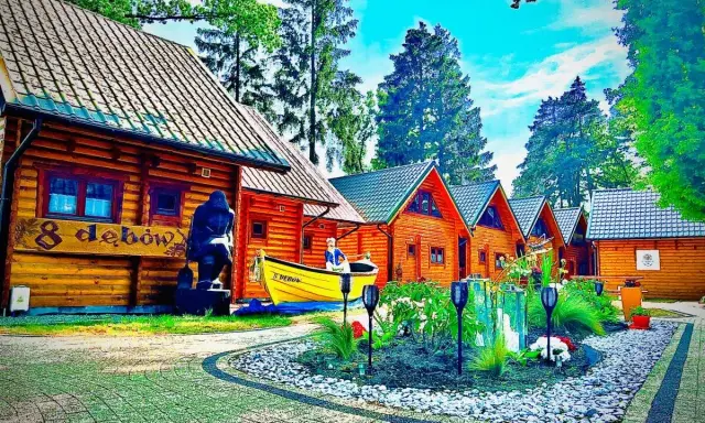 Drewniane domki z psem na tablicy. Wiosna w pełni, kwitnące krzewy i drzewa.