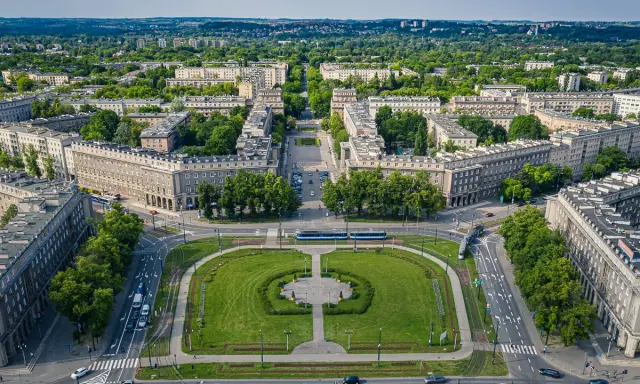 Plac Centralny w Nowej Hucie z socrealistyczną zabudową, zielonymi skwerami i torami tramwajowymi.