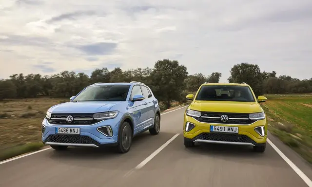 Un Volkswagen T-Cross azul y un T-Roc amarillo circulan por una carretera rural.