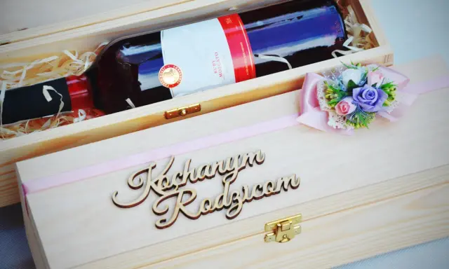 Elegancka skrzynka na wino dla chrzestnych z napisem "Kochanym Rodzicom" i ozdobną kokardką z kwiatami.