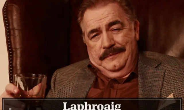 Mann mit Schnurrbart hält Glas Whisky. Die Laphroaig Aussprache ist wichtig für Kenner.