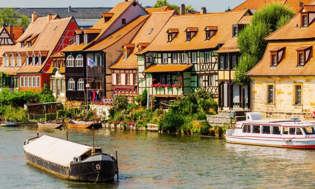 Bunte Fachwerkhäuser säumen das Wasser, Boote schaukeln sanft. Ein malerischer Anblick, der die vielen Attraktionen Bayerns widerspiegelt.