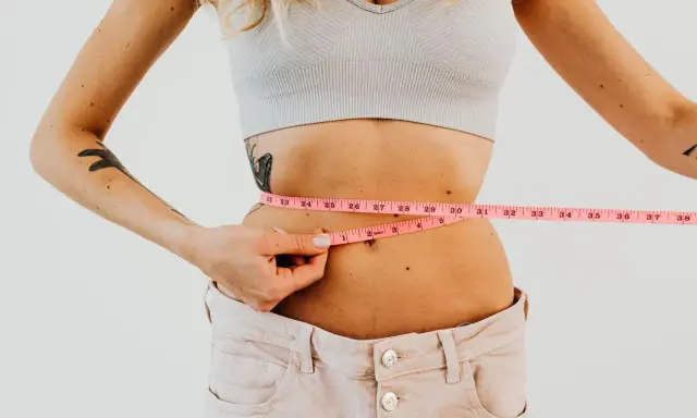 Kobieta mierzy talię centymetrem. Efekty diety 1400 kcal są widoczne.