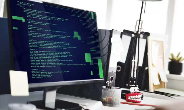 Tester oprogramowania analizuje kod na ekranie komputera.