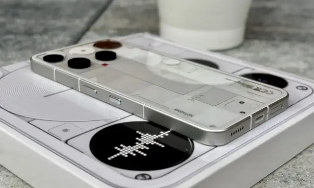 Przezroczysty telefon survivalowy z minimalistycznym designem, leżący na białym pudełku z grafiką.