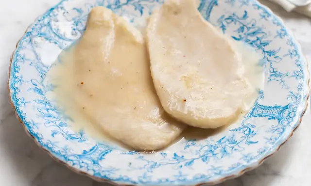 Due scaloppine al vino bianco, tenere e succulente, servite su un piatto decorato con motivi blu.