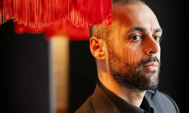 Ardalan Esmaili, med ansiktet belyst av ett randigt ljus, tittar bort.