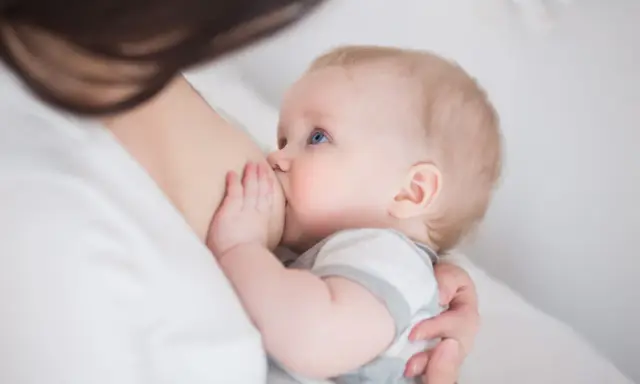 Niebieskooki niemowlak karmiony piersią. Czasem pojawia się kryzys laktacyjny, ale to naturalny etap.