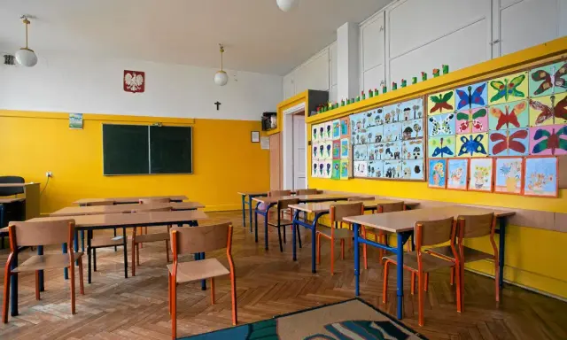 Pusta klasa z kolorowymi pracami dzieci na ścianie. Idealne miejsce, kiedy wolne od szkoły, by poczuć się jak uczeń.