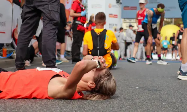 Zmęczona biegaczka leży na ziemi po tym, jak dowiedziała się, ile biegnie się maraton.