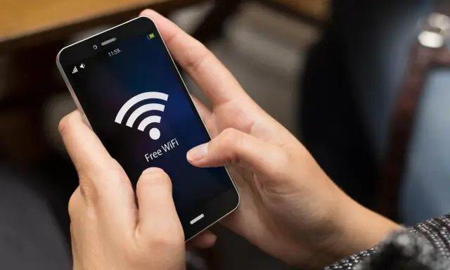 Person versucht, das Handy mit dem WLAN zu verbinden, aber es klappt nicht. Das WLAN-Symbol leuchtet auf dem Bildschirm.
